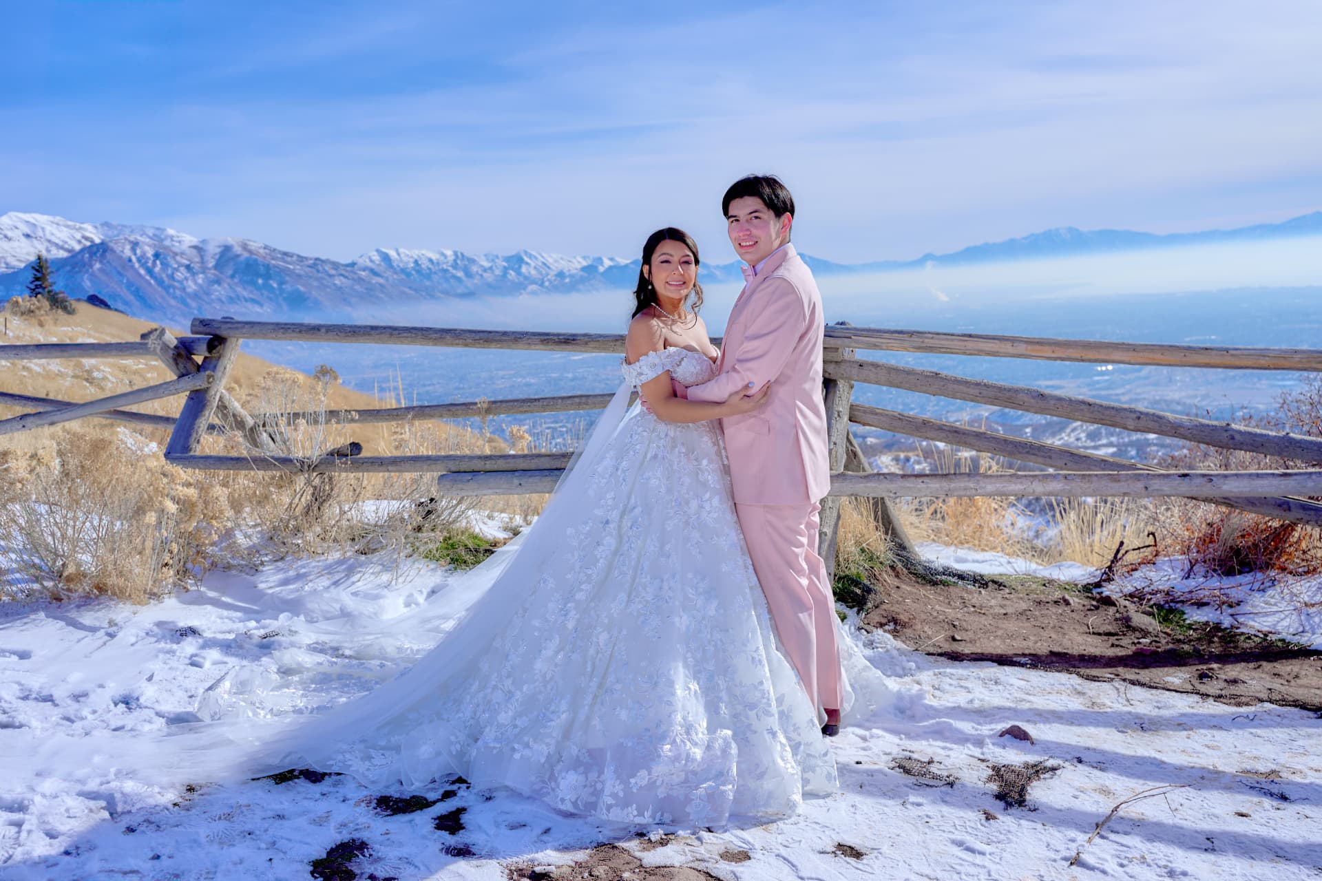 Pareja de recién casados posando en la montaña, con nieve y cielo azul de fondo